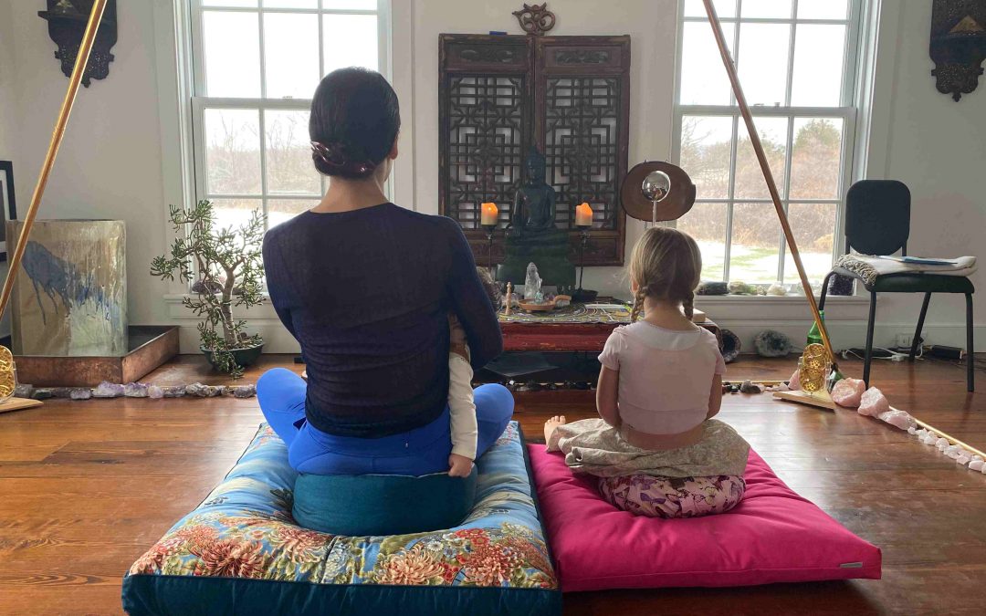 a woman sits with her daughter in a meditation room.